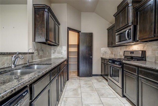 3904 Normandy Rd, Edmond, OK 73013 - kitchen with appliances with stainless steel finishes, vaulted ceiling, dark stone countertops, decorative backsplash, and dark brown cabinets