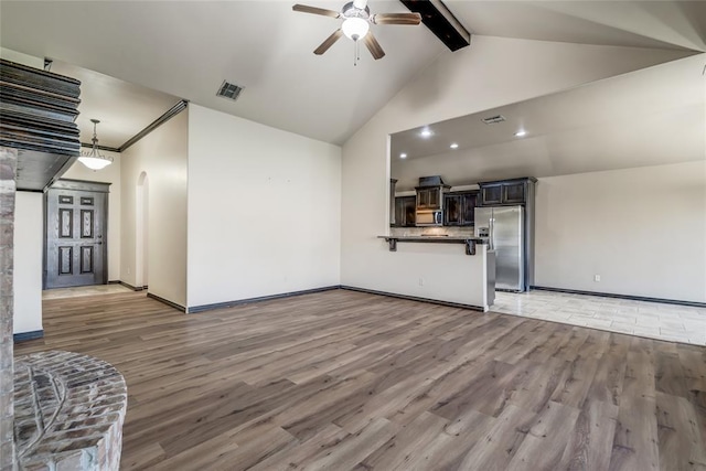 3904 Normandy Rd, Edmond, OK 73013 - unfurnished living room featuring a ceiling fan, light wood-style flooring, beamed ceiling, arched walkways, and high vaulted ceiling