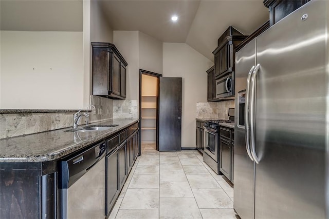 3904 Normandy Rd, Edmond, OK 73013 - kitchen featuring stainless steel appliances, dark stone counters, vaulted ceiling, tasteful backsplash, and dark brown cabinets
