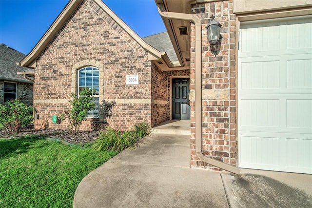 3904 Normandy Rd, Edmond, OK 73013 - view of exterior entry featuring brick siding, an attached garage, and roof with shingles