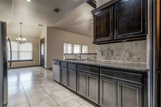 3904 Normandy Rd, Edmond, OK 73013 - kitchen featuring appliances with stainless steel finishes, a chandelier, lofted ceiling, decorative backsplash, and stone counters