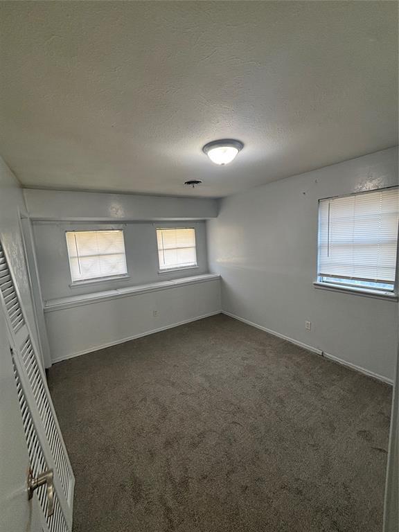 833 S Scott St, Del City, OK 73115 - spare room with a textured ceiling and dark colored carpet