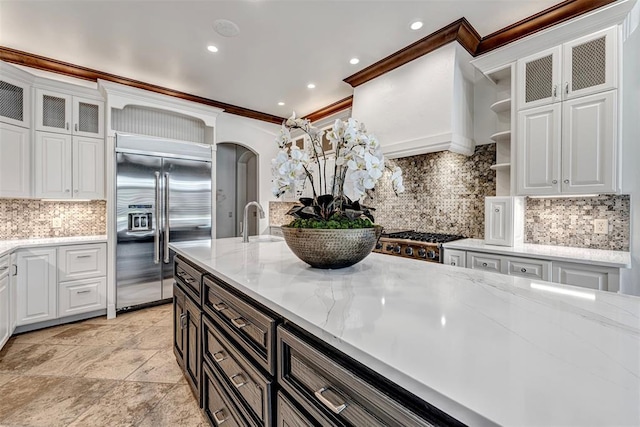 6516 NW Grand Blvd, Nichols Hills, OK 73116 - kitchen featuring appliances with stainless steel finishes, arched walkways, backsplash, white cabinetry, and ornamental molding