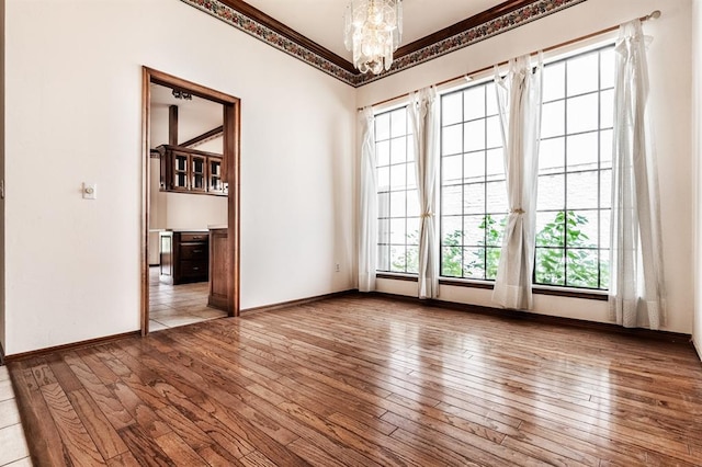 11129 Springhollow Ct, Oklahoma City, OK 73120 - unfurnished room featuring plenty of natural light, hardwood / wood-style flooring, a chandelier, and crown molding