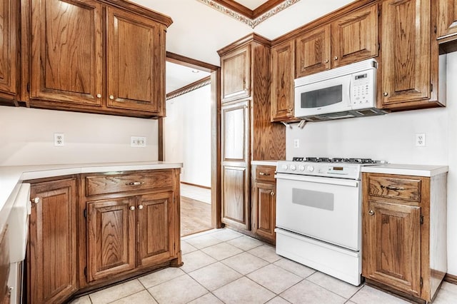 11129 Springhollow Ct, Oklahoma City, OK 73120 - kitchen featuring white appliances, brown cabinets, light countertops, light tile patterned floors, and crown molding