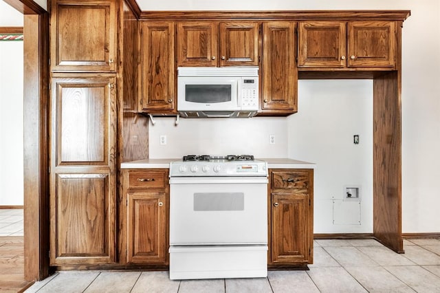 11129 Springhollow Ct, Oklahoma City, OK 73120 - kitchen with white appliances, light countertops, light tile patterned floors, and brown cabinets