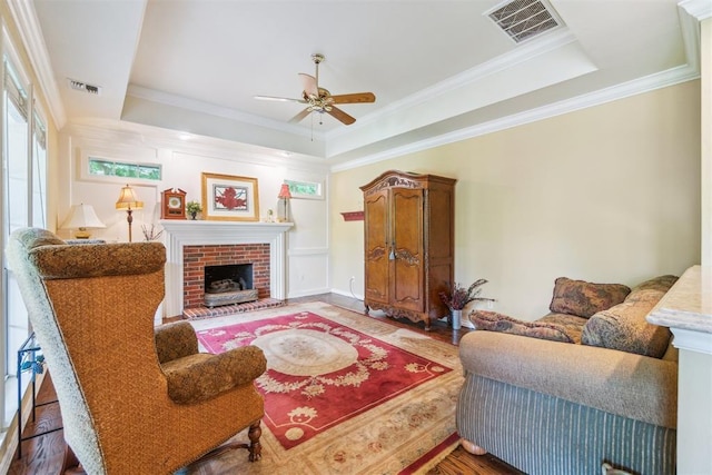 108 N Bradbury Dr, Edmond, OK 73034 - living room with a tray ceiling, a ceiling fan, wood finished floors, crown molding, and a fireplace