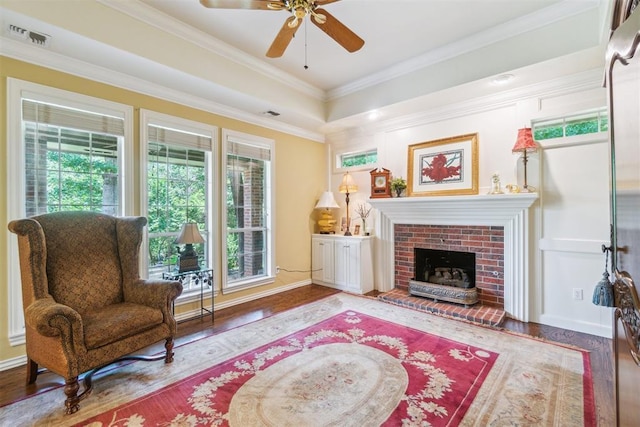 108 N Bradbury Dr, Edmond, OK 73034 - living area featuring wood finished floors, ceiling fan, crown molding, a brick fireplace, and a tray ceiling