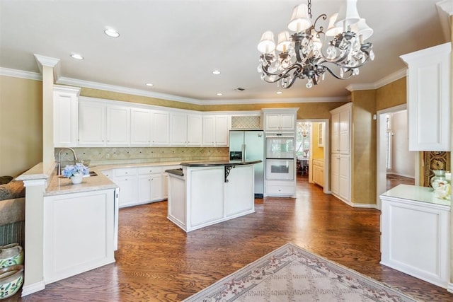 108 N Bradbury Dr, Edmond, OK 73034 - kitchen with stainless steel fridge with ice dispenser, double oven, dark wood-type flooring, white cabinets, and ornamental molding