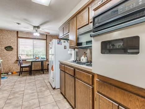1329 SW 77th Ter, Oklahoma City, OK 73159 - kitchen featuring white oven, a ceiling fan, light tile patterned flooring, stainless steel stovetop, and light countertops