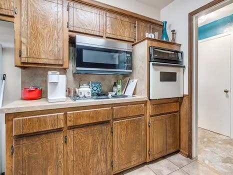1329 SW 77th Ter, Oklahoma City, OK 73159 - kitchen with white oven, stainless steel microwave, and brown cabinets