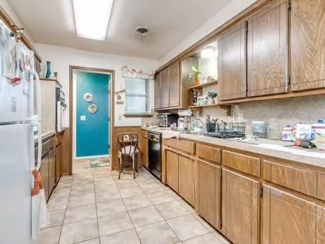 1329 SW 77th Ter, Oklahoma City, OK 73159 - kitchen featuring freestanding refrigerator, open shelves, light countertops, and light tile patterned floors