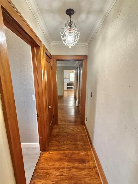 722 E Main St, Sentinel, OK 73664 - hall featuring a chandelier, wood finished floors, and ornamental molding