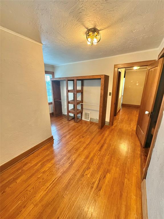 722 E Main St, Sentinel, OK 73664 - spare room with light wood-type flooring, a textured ceiling, and crown molding