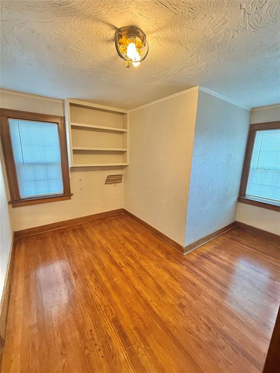 722 E Main St, Sentinel, OK 73664 - unfurnished room with wood finished floors, crown molding, and a textured ceiling