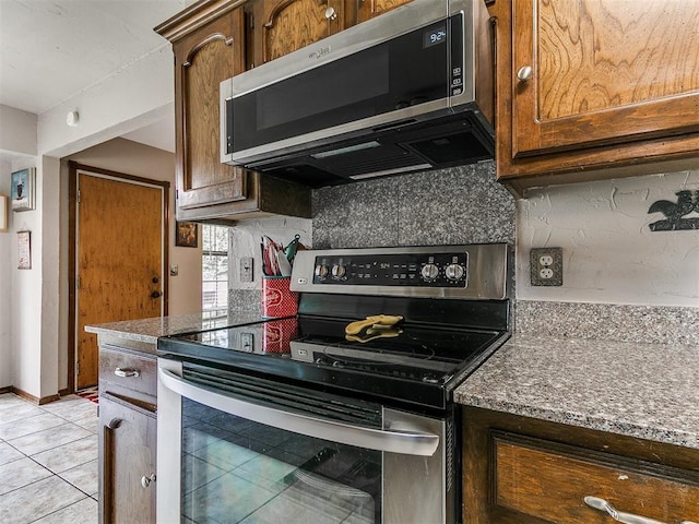 2228 Butternut Pl, Edmond, OK 73013 - kitchen featuring appliances with stainless steel finishes, tasteful backsplash, light tile patterned floors, and dark stone countertops
