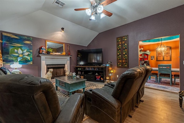 1408 Eagle Dr, Moore, OK 73160 - living area featuring a ceiling fan, wood finished floors, vaulted ceiling, a fireplace, and a chandelier