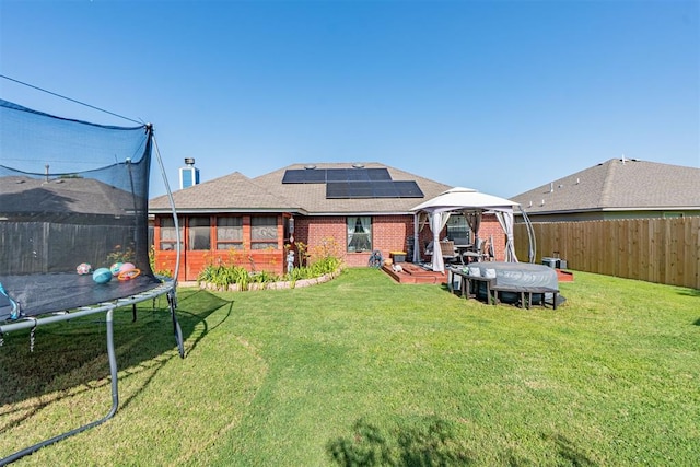1408 Eagle Dr, Moore, OK 73160 - back of property with a trampoline, a gazebo, brick siding, a fenced backyard, and a shingled roof