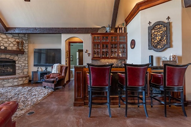 1505 SW 113th Pl, Oklahoma City, OK 73170 - indoor dry bar with finished concrete flooring, a fireplace, arched walkways, beam ceiling, and decorative backsplash