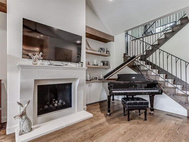 2917 Piazza Ct, Arcadia, OK 73007 - living area featuring wood finished floors, stairs, high vaulted ceiling, and a fireplace with raised hearth