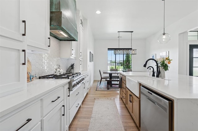 4504 SE 41st St, Moore, OK 73165 - kitchen with appliances with stainless steel finishes, wall chimney range hood, light wood-style floors, tasteful backsplash, and white cabinetry