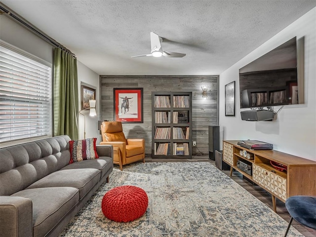 10505 Lyndon Rd, The Village, OK 73120 - living room with an accent wall, a textured ceiling, a ceiling fan, wood finished floors, and wooden walls
