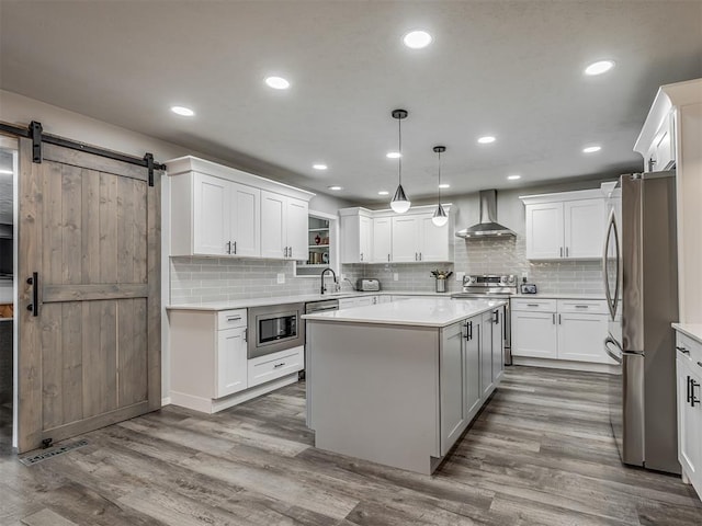 10505 Lyndon Rd, The Village, OK 73120 - kitchen with wall chimney range hood, appliances with stainless steel finishes, a kitchen island, light countertops, and recessed lighting