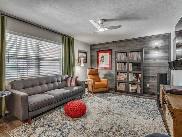 10505 Lyndon Rd, The Village, OK 73120 - living area with wood finished floors, ceiling fan, a textured ceiling, wooden walls, and an accent wall