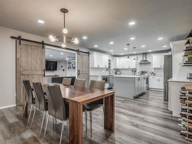 10505 Lyndon Rd, The Village, OK 73120 - dining room with a barn door, recessed lighting, and wood finished floors
