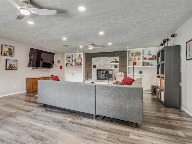 10505 Lyndon Rd, The Village, OK 73120 - living area with ceiling fan, wood finished floors, a large fireplace, a textured ceiling, and recessed lighting