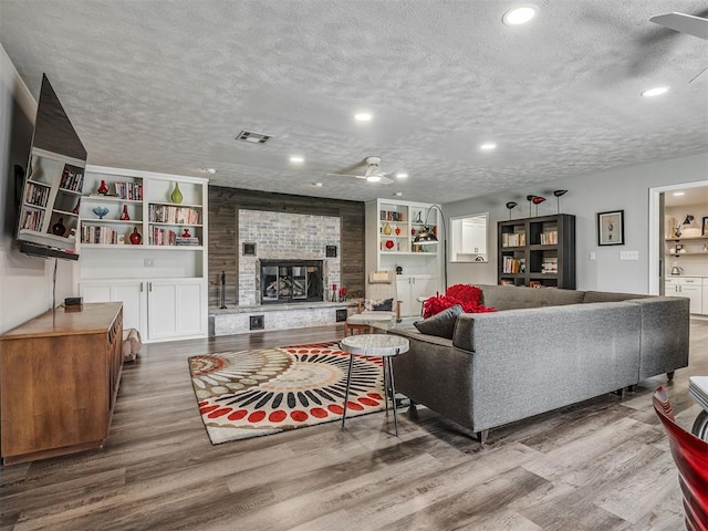 10505 Lyndon Rd, The Village, OK 73120 - living area with ceiling fan, a textured ceiling, wood finished floors, a fireplace, and recessed lighting