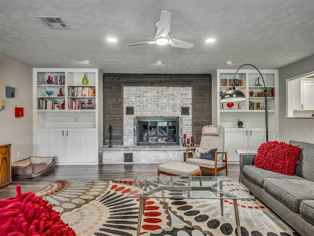 10505 Lyndon Rd, The Village, OK 73120 - living room with ceiling fan, wood finished floors, a brick fireplace, built in features, and a textured ceiling