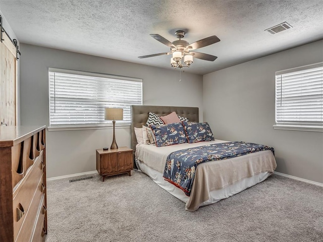10505 Lyndon Rd, The Village, OK 73120 - bedroom featuring carpet flooring, a barn door, a textured ceiling, and a ceiling fan