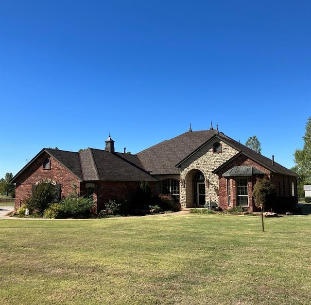 2284 Jackie Pl, Tuttle, OK 73089 - french country home featuring a front lawn, brick siding, and stone siding