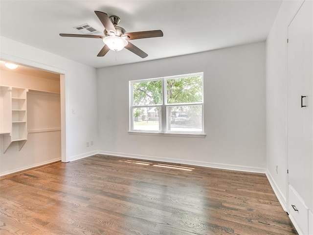 213 E Haddock St, Norman, OK 73069 - unfurnished bedroom with wood finished floors, a walk in closet, ceiling fan, and a closet