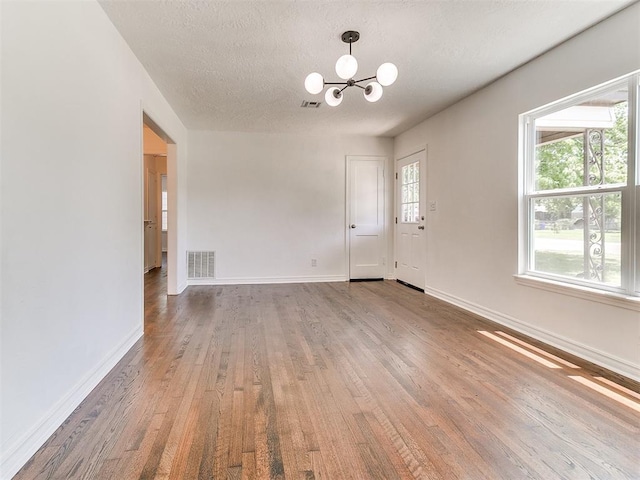 213 E Haddock St, Norman, OK 73069 - spare room featuring a chandelier, wood finished floors, and a textured ceiling