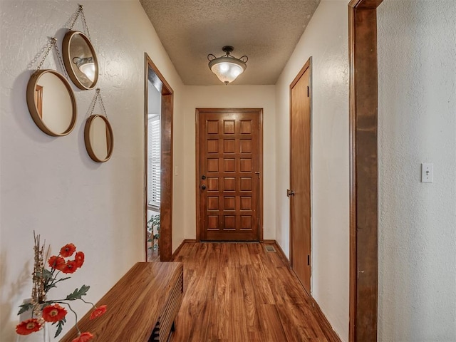 2104 Tanglewood Dr, Edmond, OK 73013 - hall featuring light wood-style flooring, a textured ceiling, and a textured wall