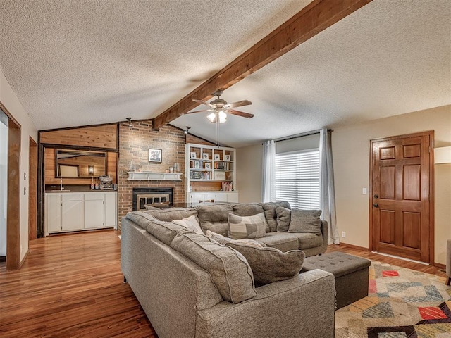 2104 Tanglewood Dr, Edmond, OK 73013 - living room featuring wood finished floors, ceiling fan, a textured ceiling, and a brick fireplace