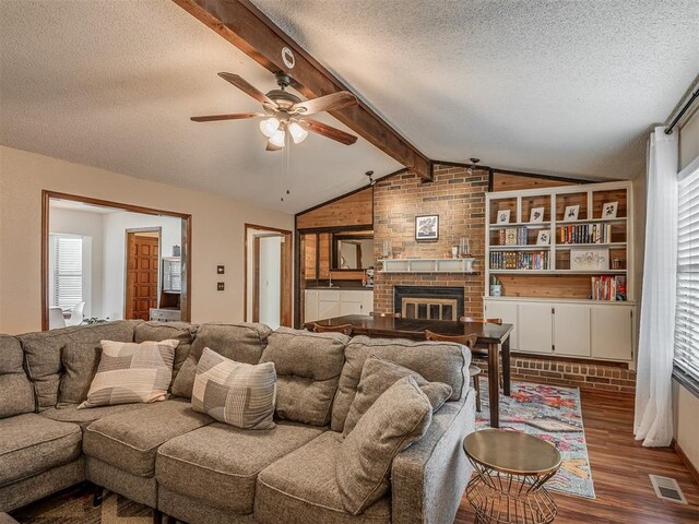 2104 Tanglewood Dr, Edmond, OK 73013 - living area with a textured ceiling, dark wood finished floors, a ceiling fan, a brick fireplace, and healthy amount of natural light