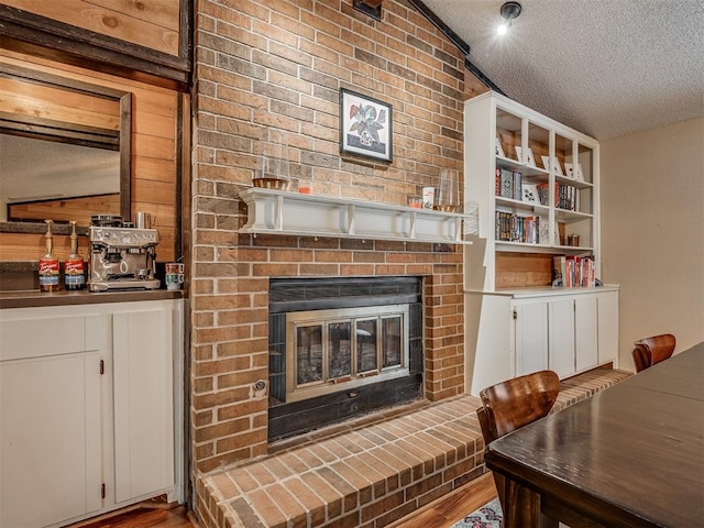 2104 Tanglewood Dr, Edmond, OK 73013 - living room featuring a textured ceiling, a fireplace, wood finished floors, and lofted ceiling