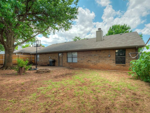 2104 Tanglewood Dr, Edmond, OK 73013 - rear view of house with an outdoor fire pit, brick siding, a chimney, and a patio