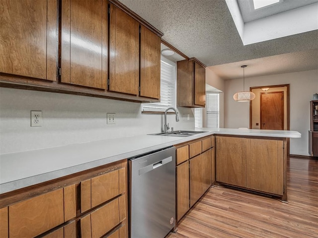 2104 Tanglewood Dr, Edmond, OK 73013 - kitchen with stainless steel dishwasher, a peninsula, light wood-type flooring, light countertops, and a textured ceiling