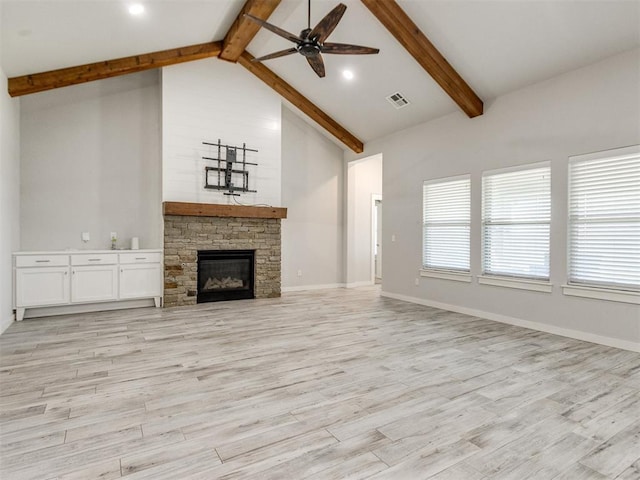 6713 NW 149th St, Oklahoma City, OK 73142 - unfurnished living room featuring a ceiling fan, beam ceiling, light wood finished floors, a stone fireplace, and high vaulted ceiling