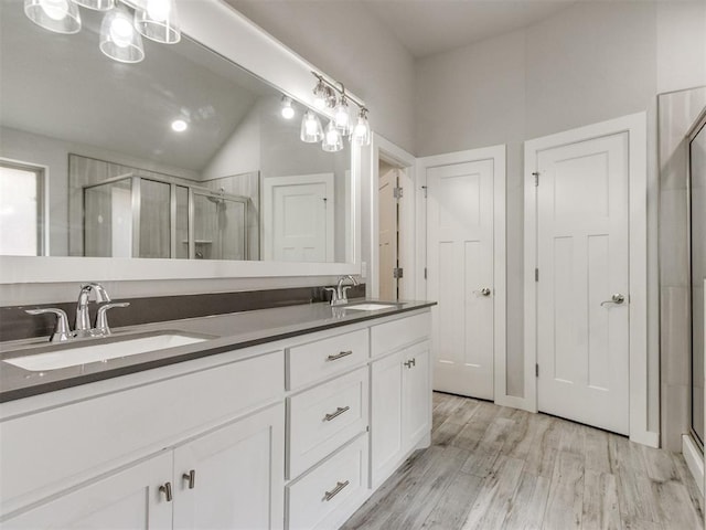 6713 NW 149th St, Oklahoma City, OK 73142 - bathroom featuring double vanity, a shower stall, vaulted ceiling, and wood finished floors