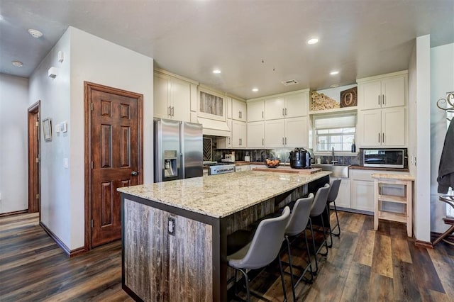 1187 County St Unit 2976, Blanchard, OK 73010 - kitchen with stainless steel appliances, a center island, dark wood finished floors, light stone countertops, and backsplash