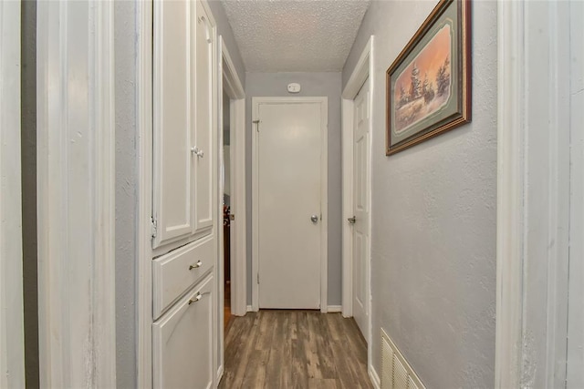5505 S Dimple Dr, Oklahoma City, OK 73135 - hallway featuring a textured ceiling and dark wood-type flooring