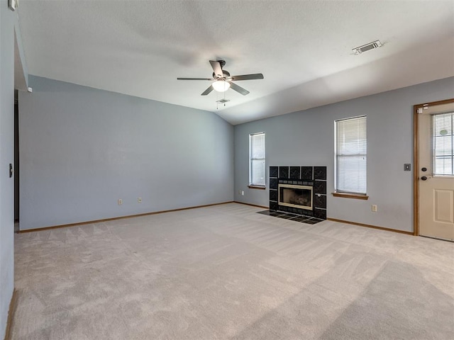 321 Bradgate Dr, Yukon, OK 73099 - unfurnished living room featuring plenty of natural light, a ceiling fan, light carpet, a tiled fireplace, and a textured ceiling