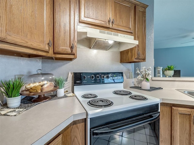 321 Bradgate Dr, Yukon, OK 73099 - kitchen featuring black / electric stove, under cabinet range hood, brown cabinets, light countertops, and tile patterned flooring