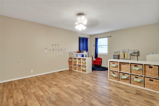 4213 NE 143rd St, Edmond, OK 73013 - playroom with wood finished floors, a textured ceiling, and a ceiling fan