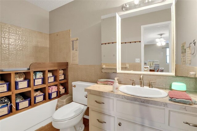 4213 NE 143rd St, Edmond, OK 73013 - full bathroom with vanity, tile walls, washtub / shower combination, a textured ceiling, and a ceiling fan